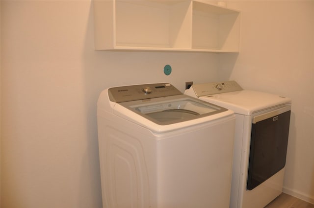 laundry area with separate washer and dryer and light hardwood / wood-style floors