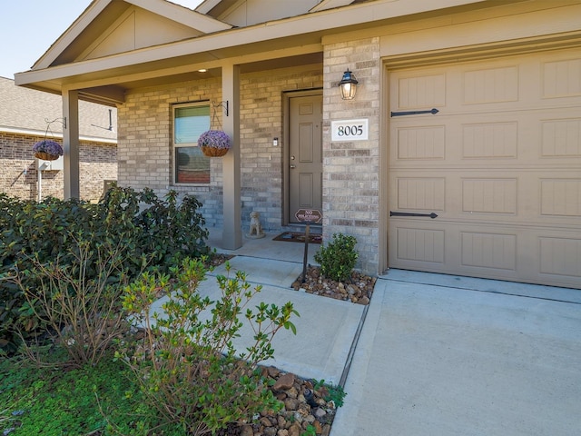 property entrance featuring brick siding, covered porch, and an attached garage