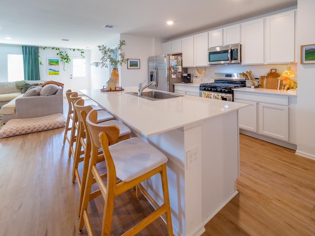 kitchen with a breakfast bar area, visible vents, a sink, appliances with stainless steel finishes, and white cabinetry