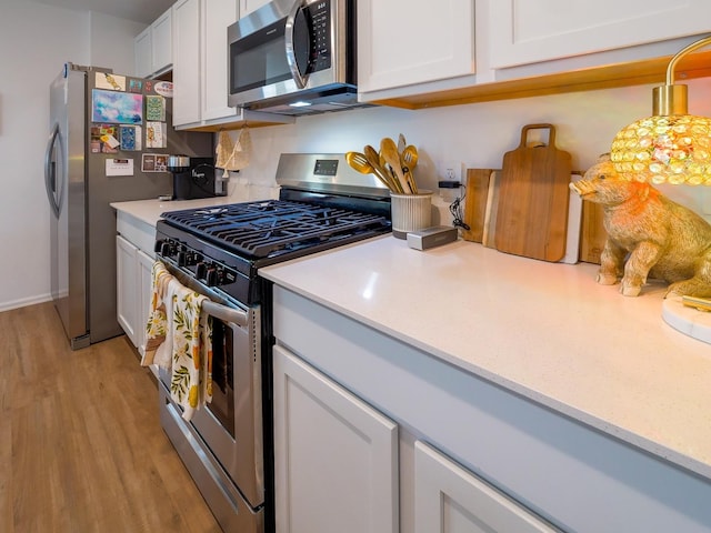 kitchen featuring light countertops, white cabinets, light wood finished floors, and stainless steel appliances