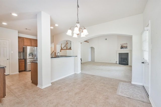 kitchen featuring sink, a chandelier, stainless steel fridge with ice dispenser, hanging light fixtures, and light colored carpet