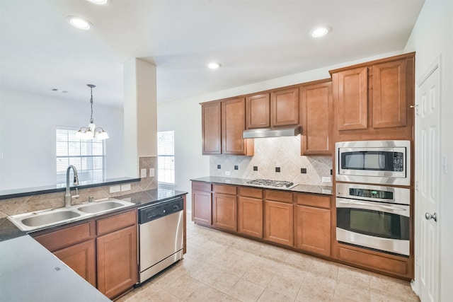 kitchen with appliances with stainless steel finishes, sink, decorative backsplash, hanging light fixtures, and a notable chandelier