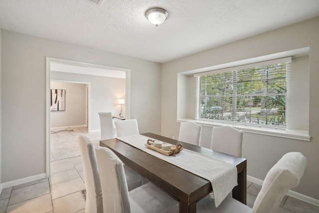 dining area with a textured ceiling and light tile patterned flooring