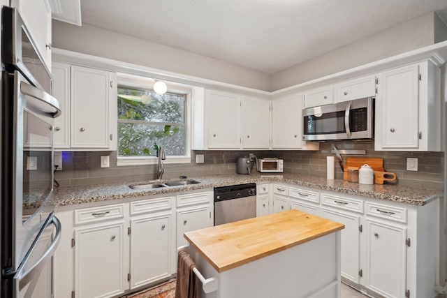 kitchen with white cabinets, light stone counters, sink, and stainless steel appliances