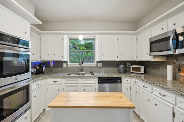 kitchen featuring white cabinets, sink, light stone countertops, and stainless steel appliances