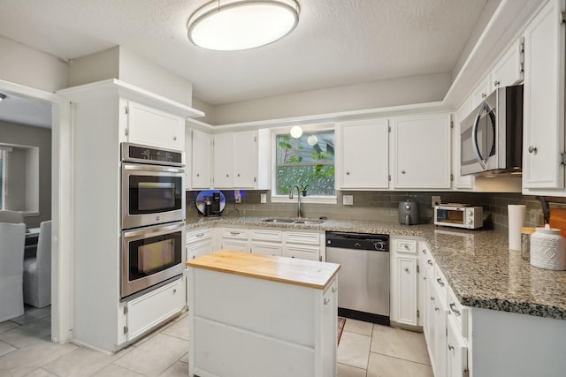 kitchen featuring a center island, dark stone counters, sink, white cabinetry, and stainless steel appliances