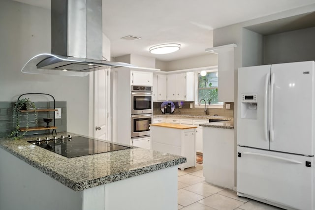 kitchen featuring white cabinetry, light stone countertops, white fridge with ice dispenser, island exhaust hood, and black electric cooktop