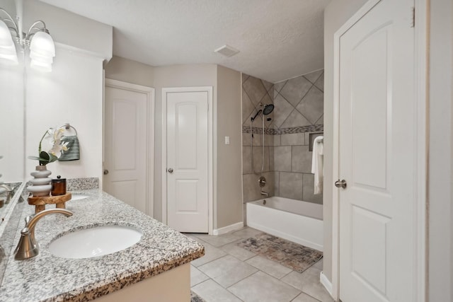 bathroom with tile patterned floors, vanity, a textured ceiling, and tiled shower / bath