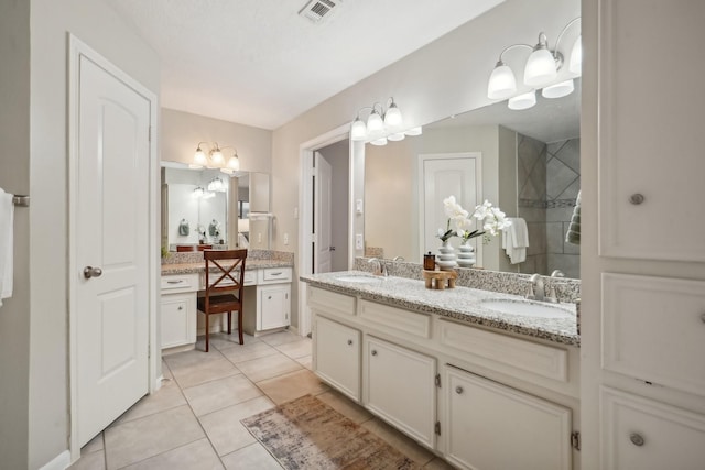 bathroom featuring tile patterned flooring, vanity, and tiled shower