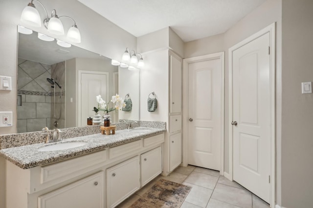 bathroom featuring a tile shower, vanity, and tile patterned floors