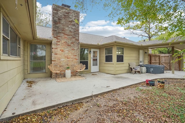 rear view of property with a patio and a hot tub