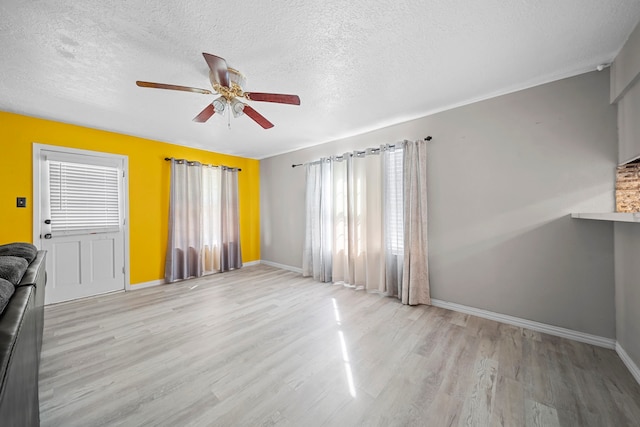 unfurnished living room with ceiling fan, a healthy amount of sunlight, a textured ceiling, and light wood-type flooring