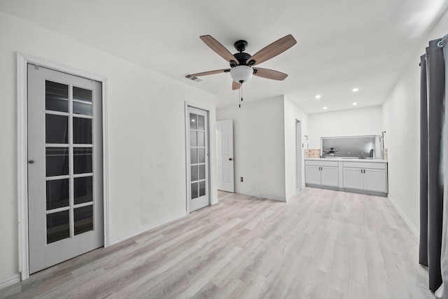 unfurnished living room featuring ceiling fan, french doors, and light wood-type flooring