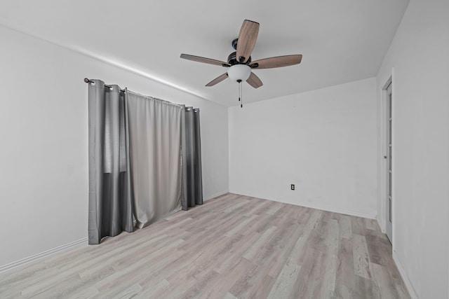 empty room with ceiling fan and light hardwood / wood-style flooring