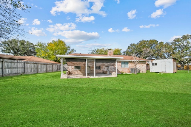 rear view of property featuring a yard, a storage shed, and a patio area