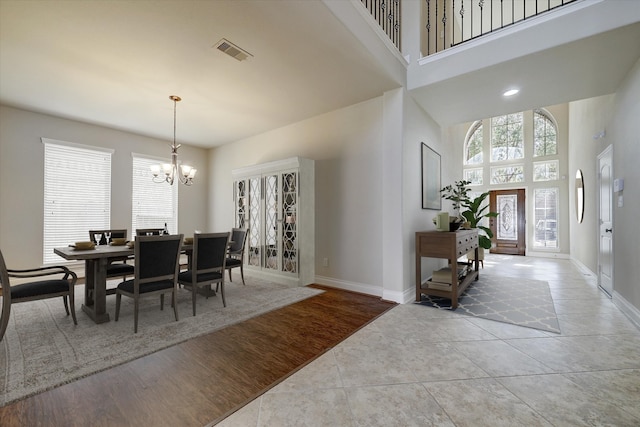 dining room with light hardwood / wood-style flooring, a high ceiling, and an inviting chandelier