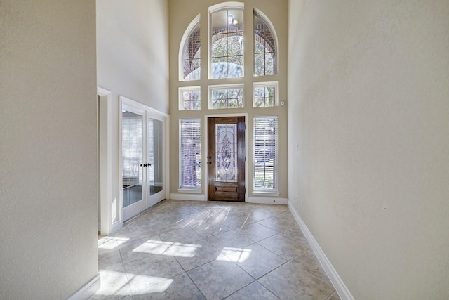 tiled foyer entrance featuring a towering ceiling and french doors