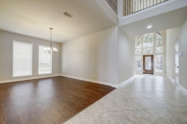 entryway featuring a chandelier, a towering ceiling, and light hardwood / wood-style flooring