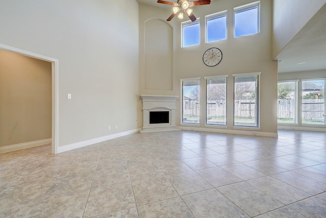 unfurnished living room featuring plenty of natural light, ceiling fan, a towering ceiling, and light tile patterned floors