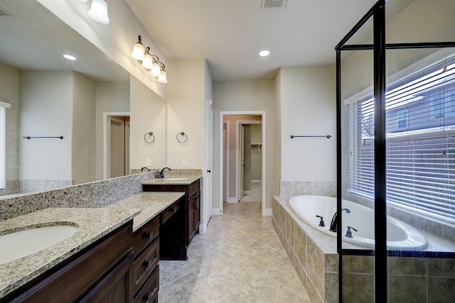 bathroom featuring tile patterned floors, vanity, and tiled tub