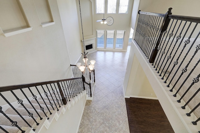 stairs with a chandelier, a towering ceiling, and tile patterned flooring