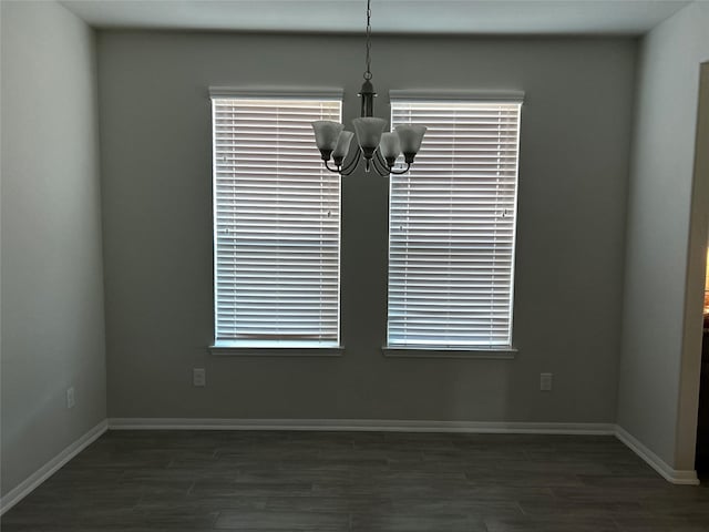 unfurnished dining area with dark wood-type flooring and a chandelier