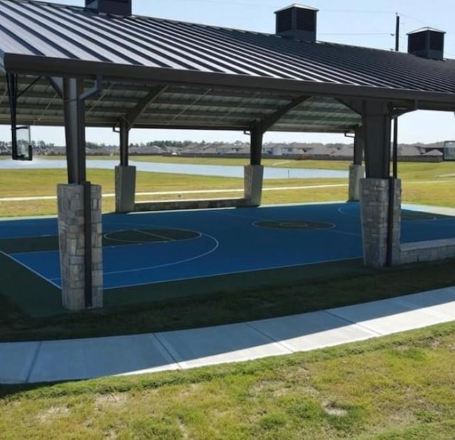 view of basketball court featuring a water view and a lawn