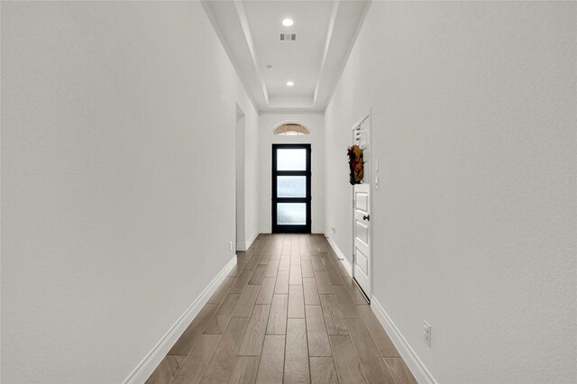 hallway with a tray ceiling and hardwood / wood-style flooring