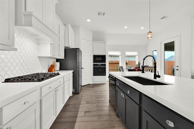 kitchen with black appliances, white cabinets, sink, tasteful backsplash, and decorative light fixtures