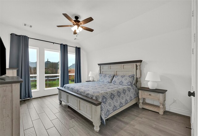 bedroom with hardwood / wood-style flooring, vaulted ceiling, and ceiling fan