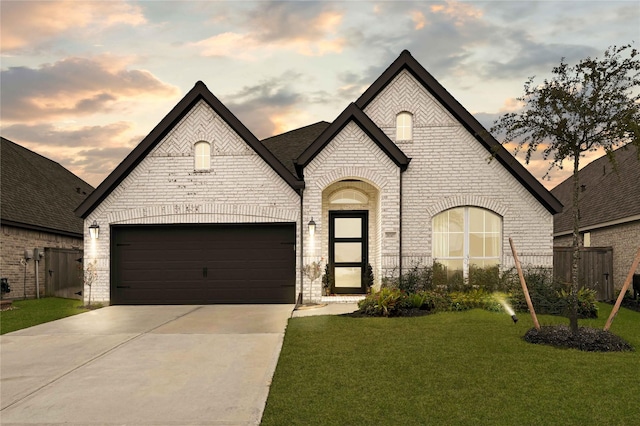 french country inspired facade featuring a garage and a lawn