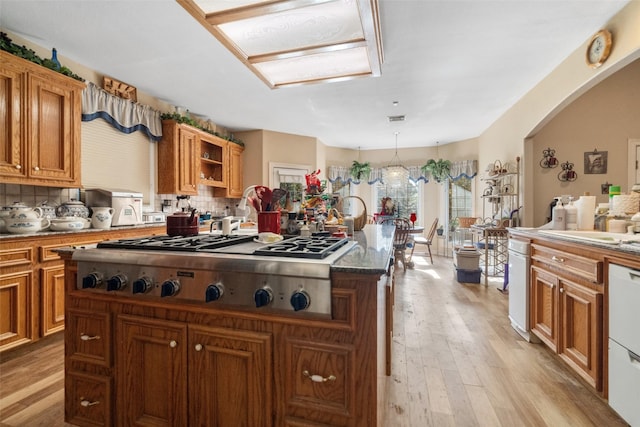 kitchen featuring a center island, stainless steel gas cooktop, backsplash, light hardwood / wood-style floors, and decorative light fixtures