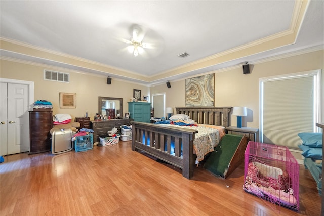 bedroom featuring a raised ceiling, crown molding, ceiling fan, and hardwood / wood-style flooring