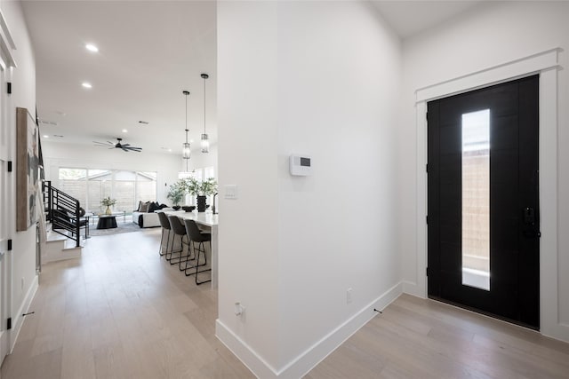 foyer entrance with ceiling fan and light wood-type flooring