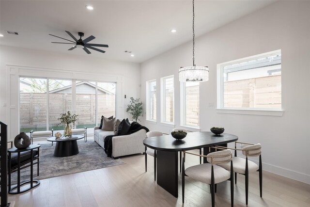 dining area with ceiling fan with notable chandelier and light wood-type flooring