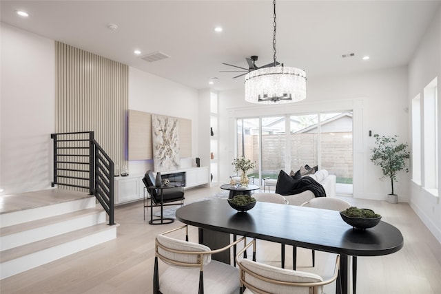 dining room featuring ceiling fan with notable chandelier and light hardwood / wood-style floors