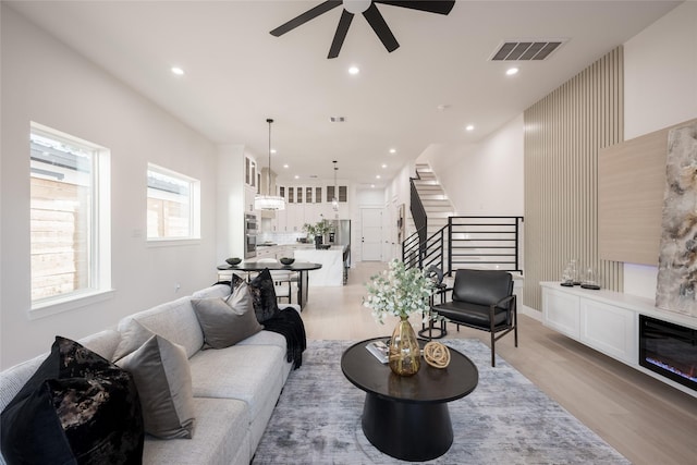 living room with light hardwood / wood-style flooring and ceiling fan