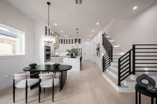 dining space with light hardwood / wood-style floors and an inviting chandelier