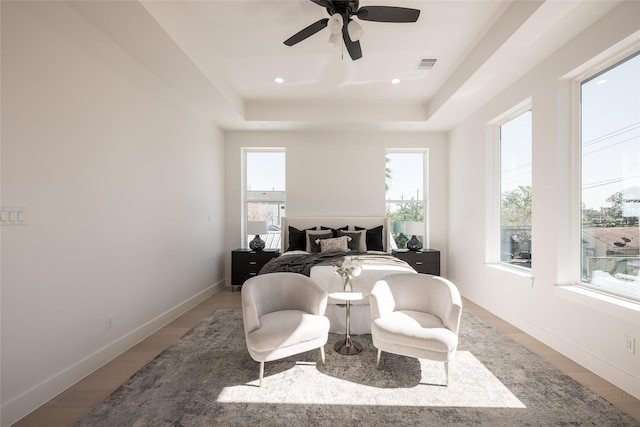 bedroom featuring ceiling fan, a raised ceiling, and wood-type flooring