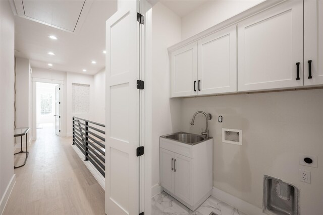 laundry room featuring cabinets, hookup for a washing machine, electric dryer hookup, sink, and light hardwood / wood-style flooring