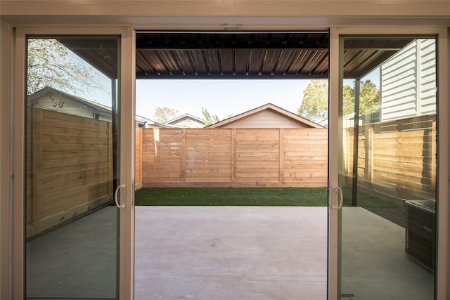 doorway to outside featuring a wealth of natural light, concrete flooring, and wood walls