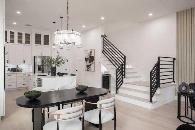 dining room featuring sink, light hardwood / wood-style floors, and a chandelier