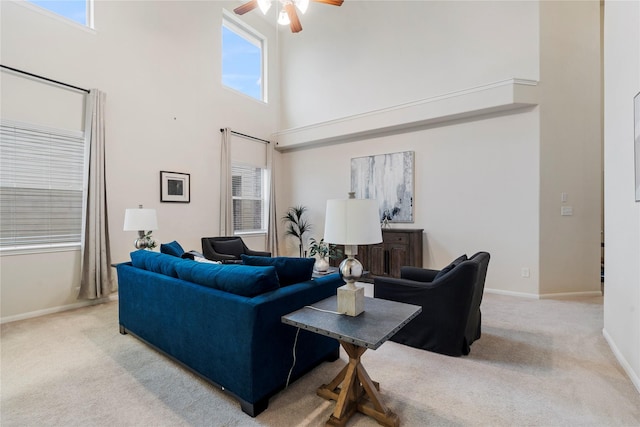 carpeted living area featuring a high ceiling, baseboards, and a ceiling fan