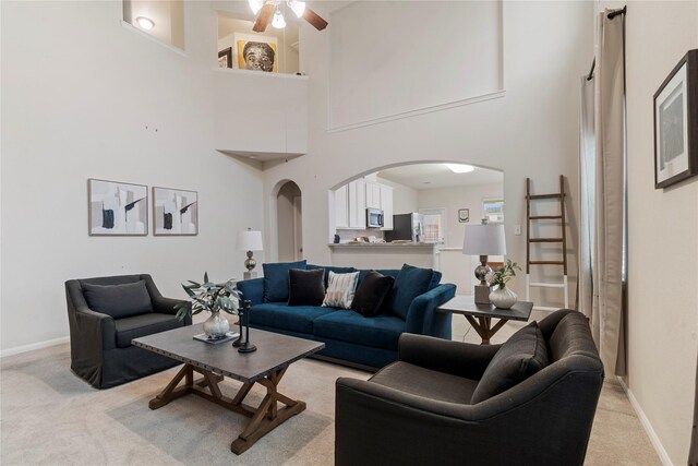 carpeted living room with ceiling fan and a high ceiling