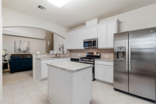 kitchen with stainless steel appliances, tasteful backsplash, light countertops, visible vents, and a sink