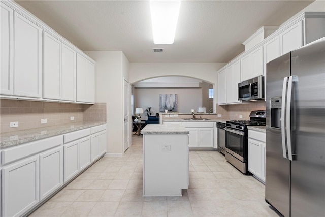 kitchen featuring arched walkways, stainless steel appliances, a sink, visible vents, and light countertops