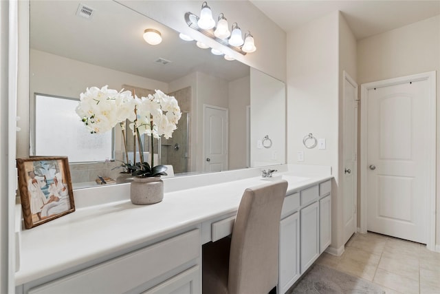 bathroom featuring vanity, a tile shower, visible vents, and tile patterned floors