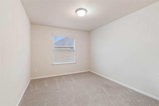 carpeted empty room featuring baseboards