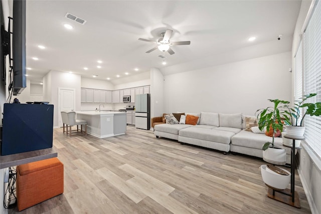 living room with ceiling fan, sink, and light hardwood / wood-style floors