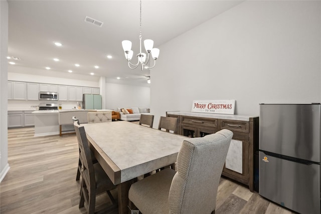 dining space featuring an inviting chandelier and light wood-type flooring